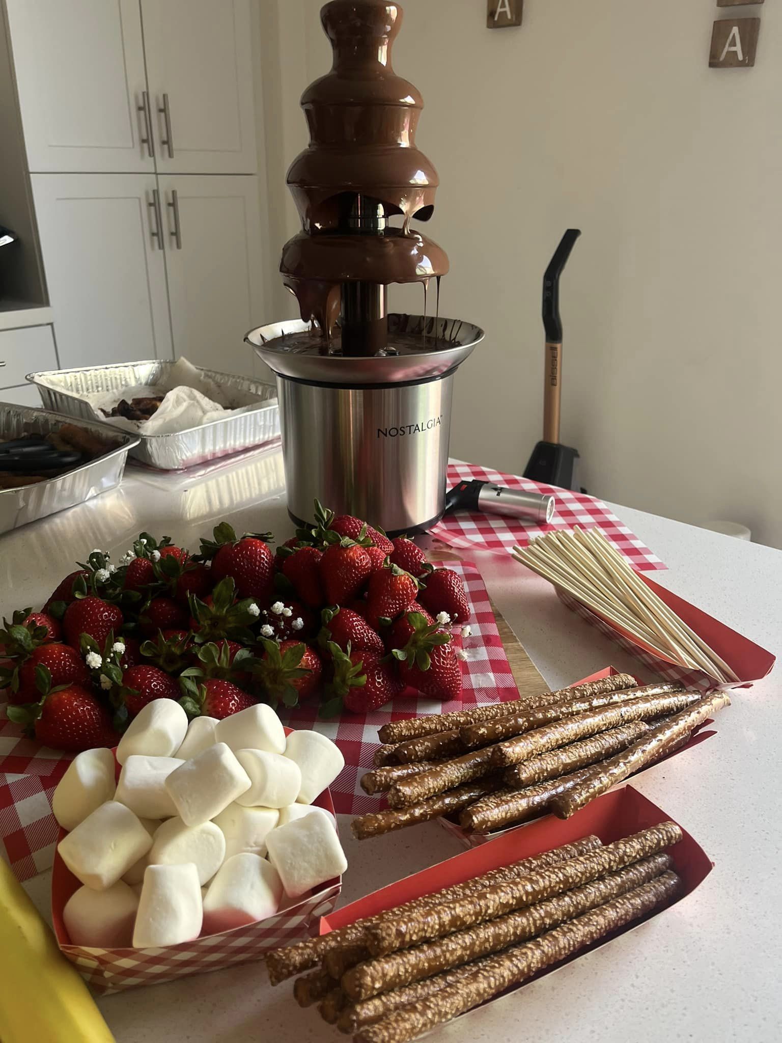 A chocolate fondue station with skewers, fruits, and marshmallows